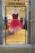 A vibrant red and pink feathered dress displayed on a mannequin inside a high-end fashion boutique. The dress has a heart-shaped neckline and a flamboyant feathered skirt. The background showcases other elegant gowns in various shades, creating a luxurious and sophisticated ambiance.