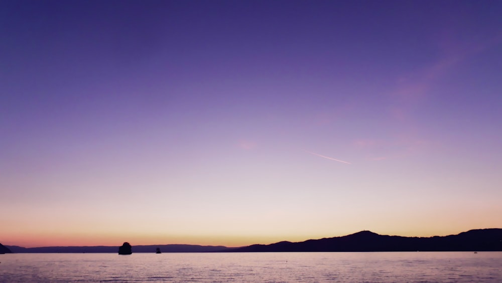 a large body of water sitting under a purple sky