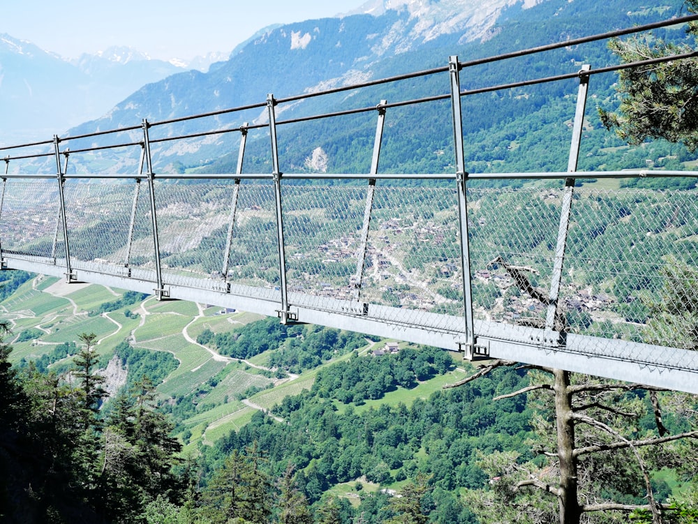 a suspension bridge over a valley with mountains in the background