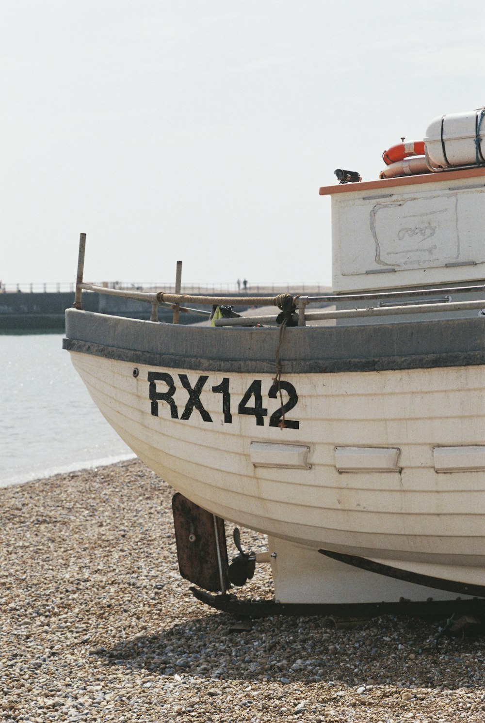 a boat sitting on top of a beach next to a body of water