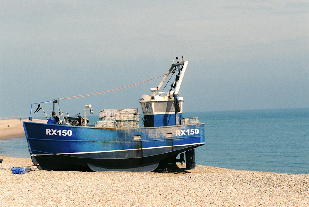 a blue boat sitting on top of a sandy beach