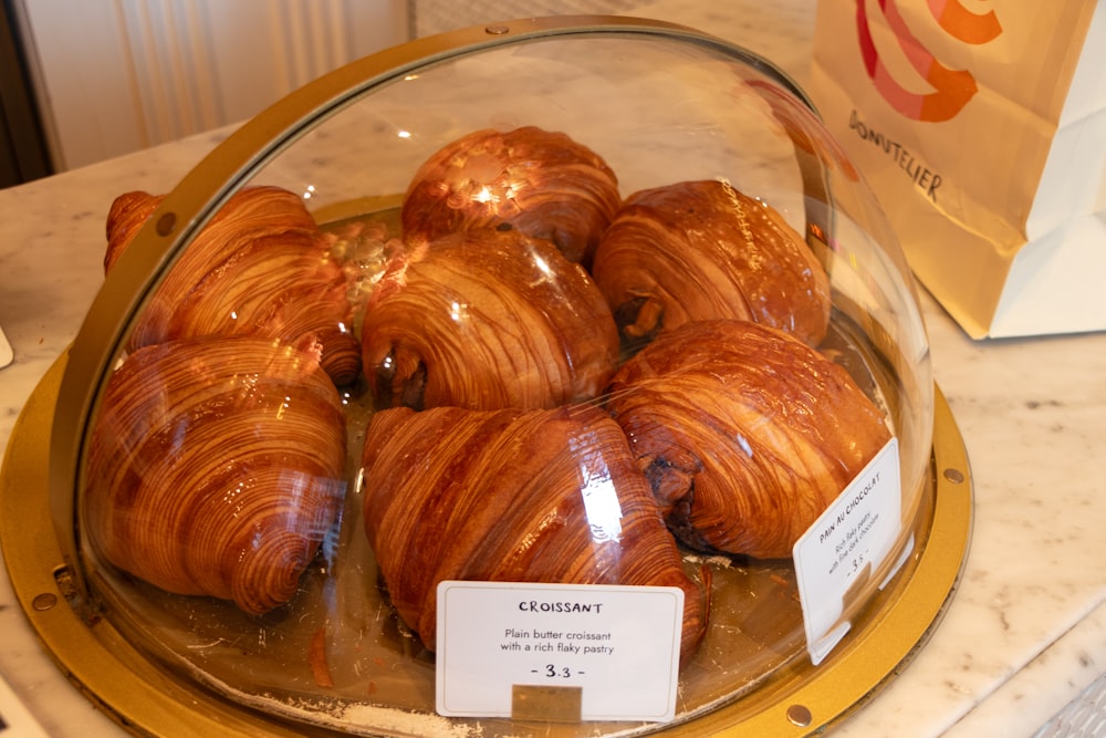 a glass display case filled with croissants on top of a counter