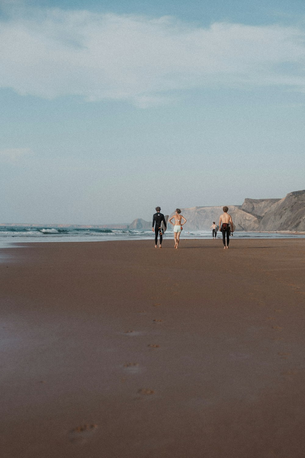 a group of people walking along a sandy beach