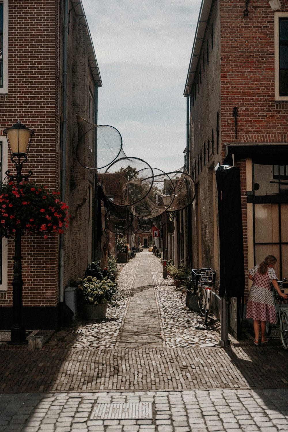 a woman is standing on a cobblestone street