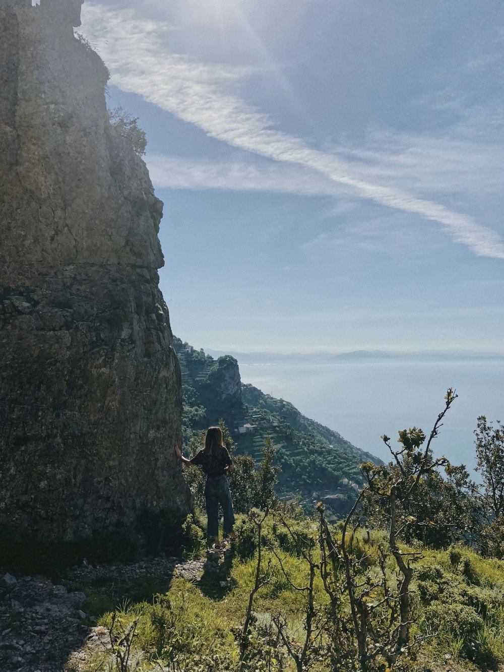 a woman standing on top of a lush green hillside