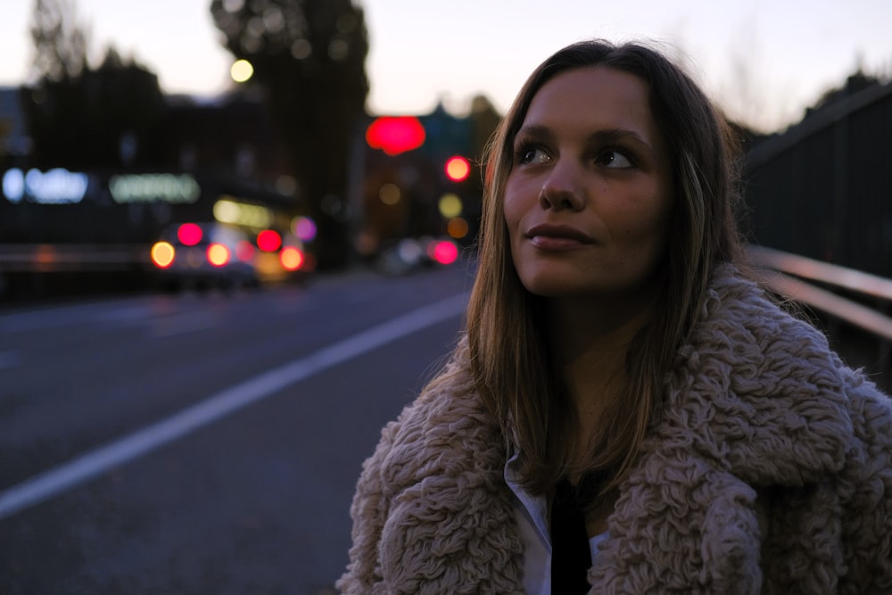 a woman standing on the side of a road at night