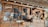 A wooden wall displays an assortment of traditional masks and handcrafted items. Several masks with expressive faces are arranged alongside woven gourds and decorative objects, including a wooden fish sculpture and an ornamental fan. The design reflects a rustic, cultural collection.