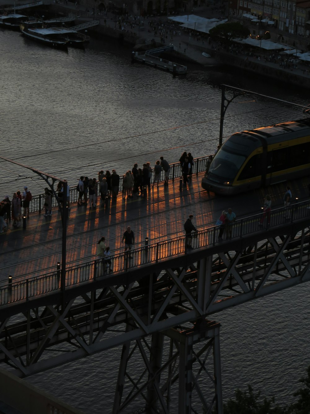 a group of people standing on a bridge next to a train