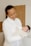 Smiling mother holding a newborn dressed in cozy baby clothes indoors.