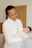 Smiling mother holding a newborn dressed in cozy baby clothes indoors.