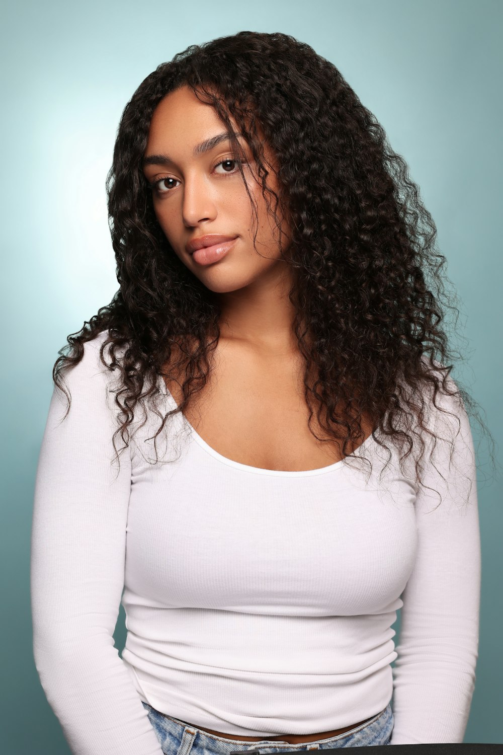 a woman with long curly hair posing for a picture