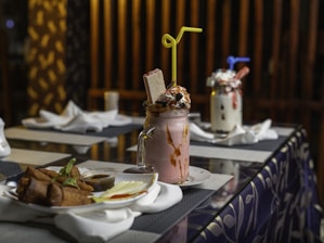 A colorful display of fresh juices, creamy milkshakes, and crispy fried chicken pieces arranged invitingly on a rustic wooden table.