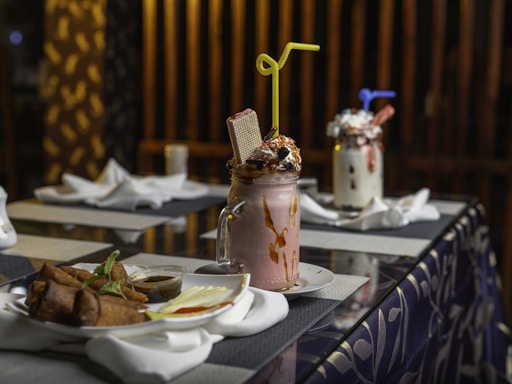 A colorful display of fresh juices, creamy milkshakes, and crispy fried chicken pieces arranged invitingly on a rustic wooden table.