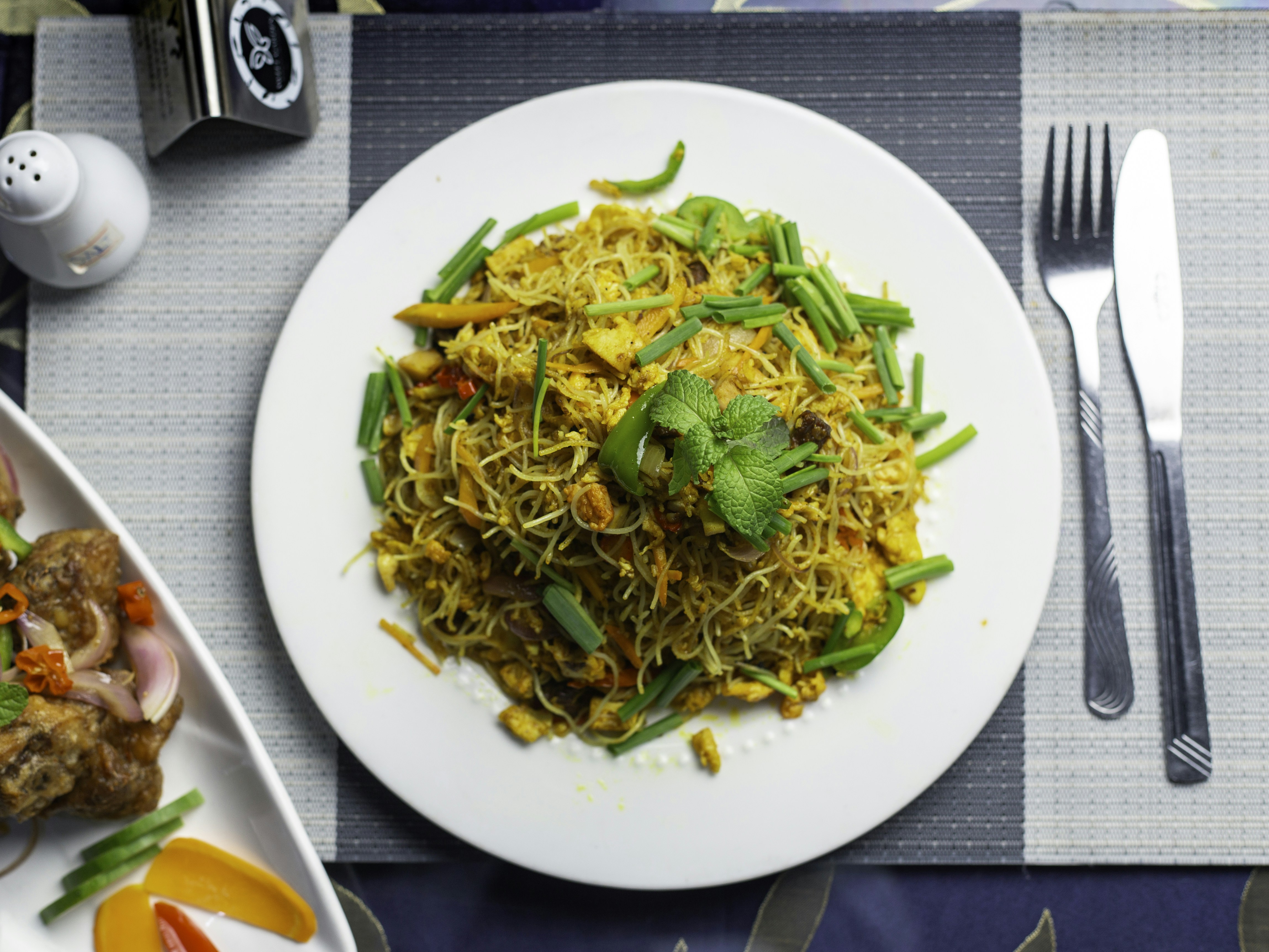 A white plate topped with food next to a fork and knife photo Free