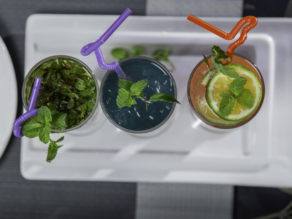 three glasses of different kinds of drinks on a tray