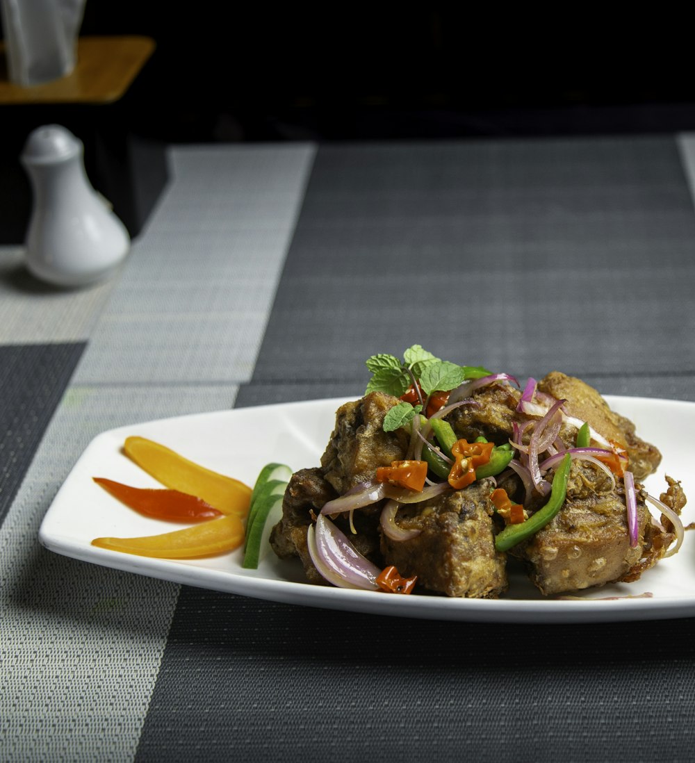 a white plate topped with meat and veggies