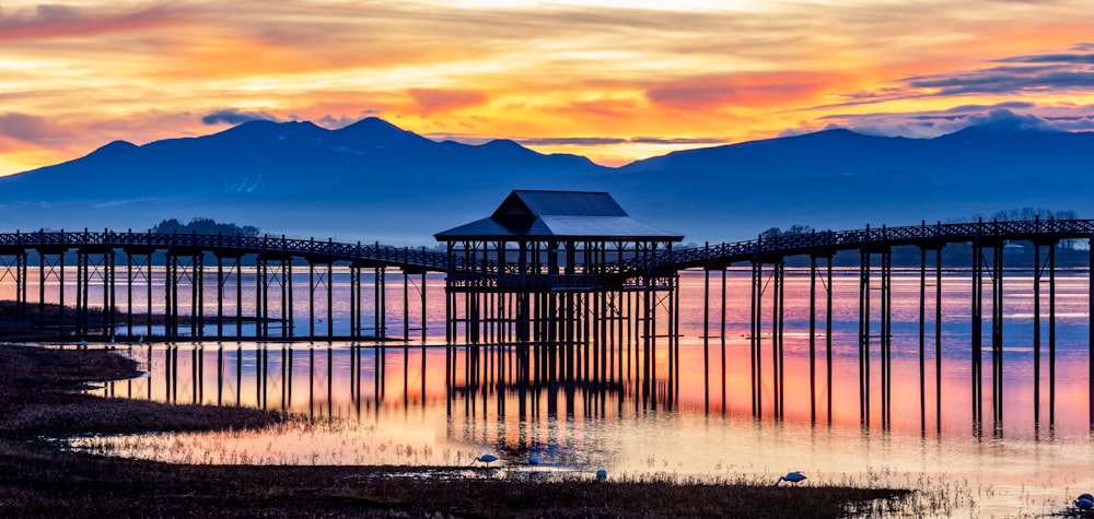 a beautiful sunset over a body of water with a pier in the foreground