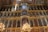 A richly decorated, multi-tiered iconostasis adorned with numerous religious paintings and ornate gold detailing. Brightly lit chandeliers cast a warm glow across the opulent structure, which features a combination of biblical figures and intricate carvings.