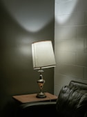 A dimly lit corner featuring a vintage lamp and a single cocktail on a side table.
