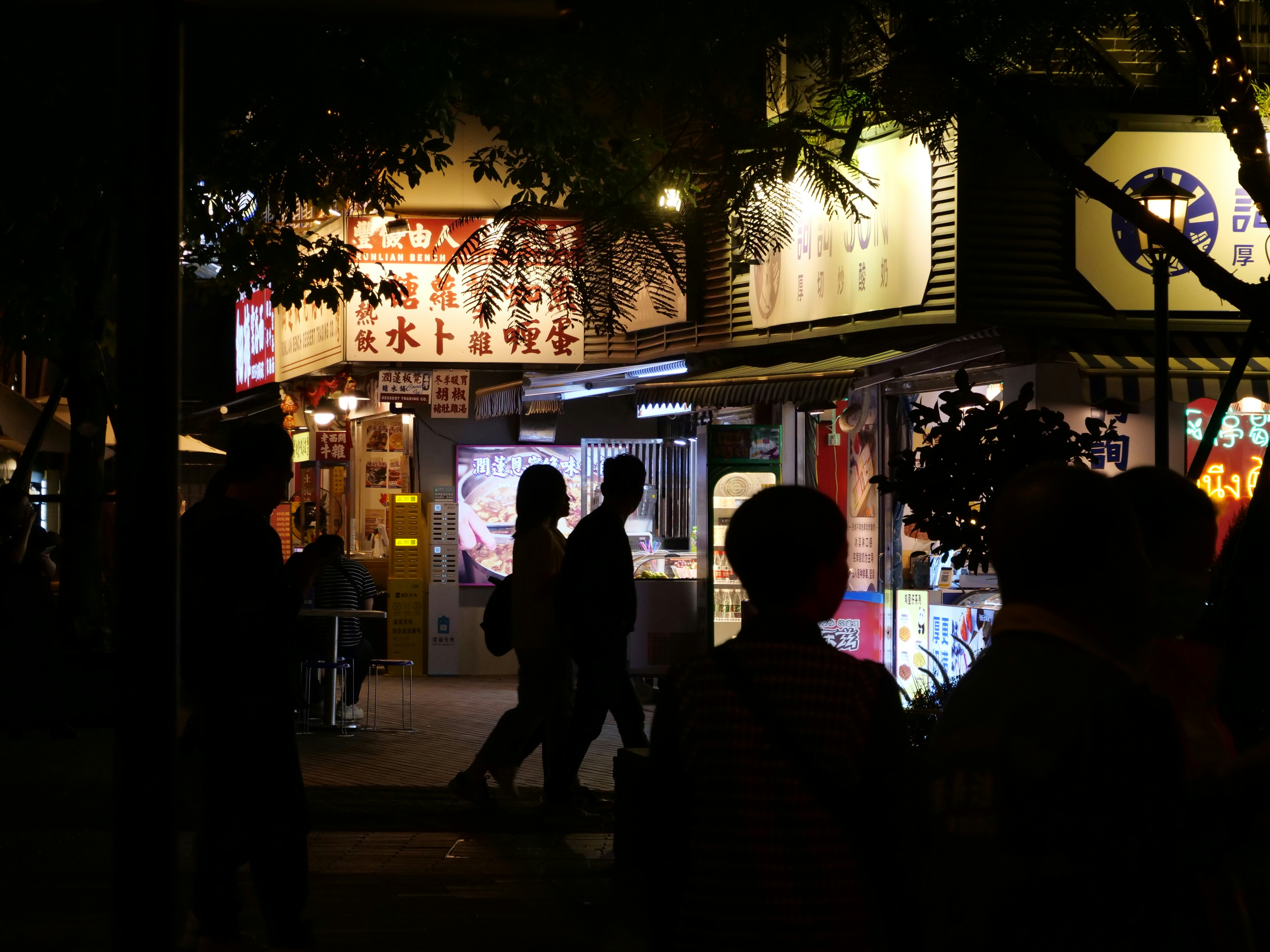a group of people walking down a street at night