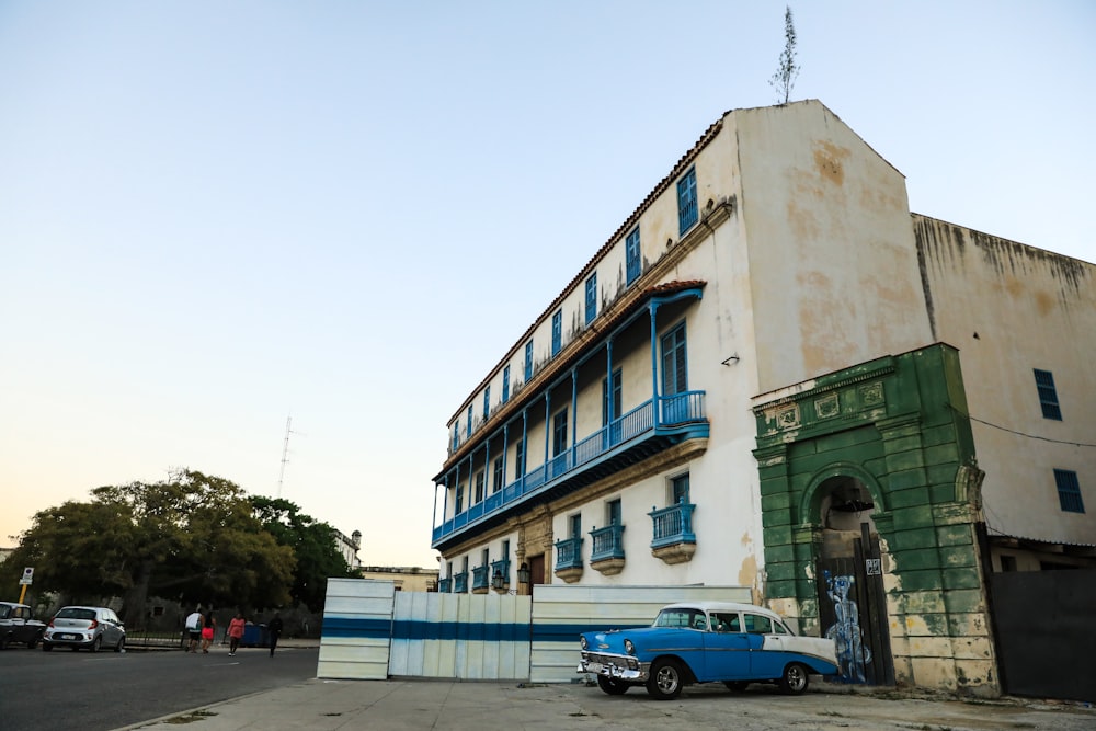 an old building with a blue car parked in front of it