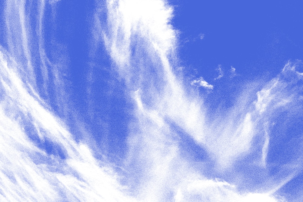 a plane flying through a blue cloudy sky