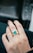 Close-up of a hand wearing a sparkling 18k gold ring with a vivid Colombian emerald.