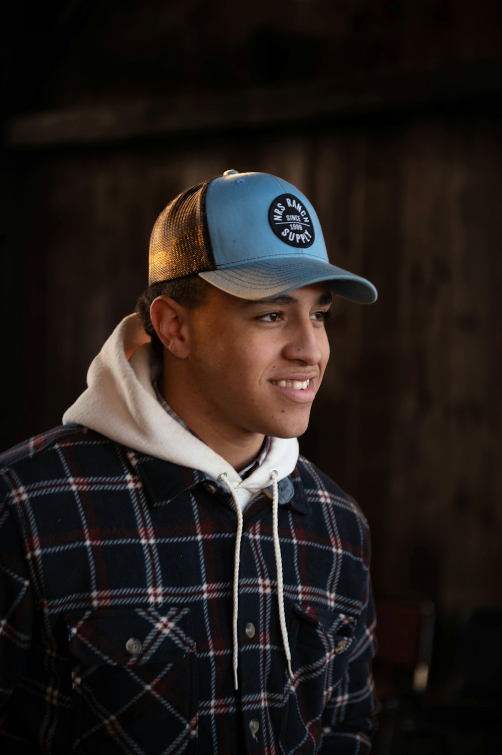 a young man wearing a blue and brown hat