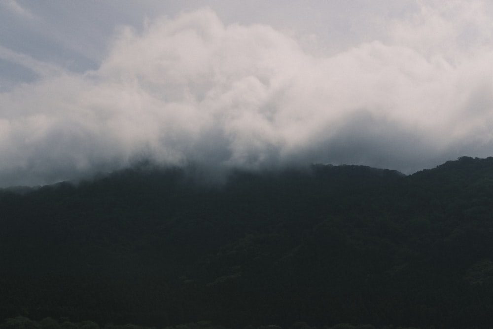 una montaña cubierta de nubes con un barco en primer plano