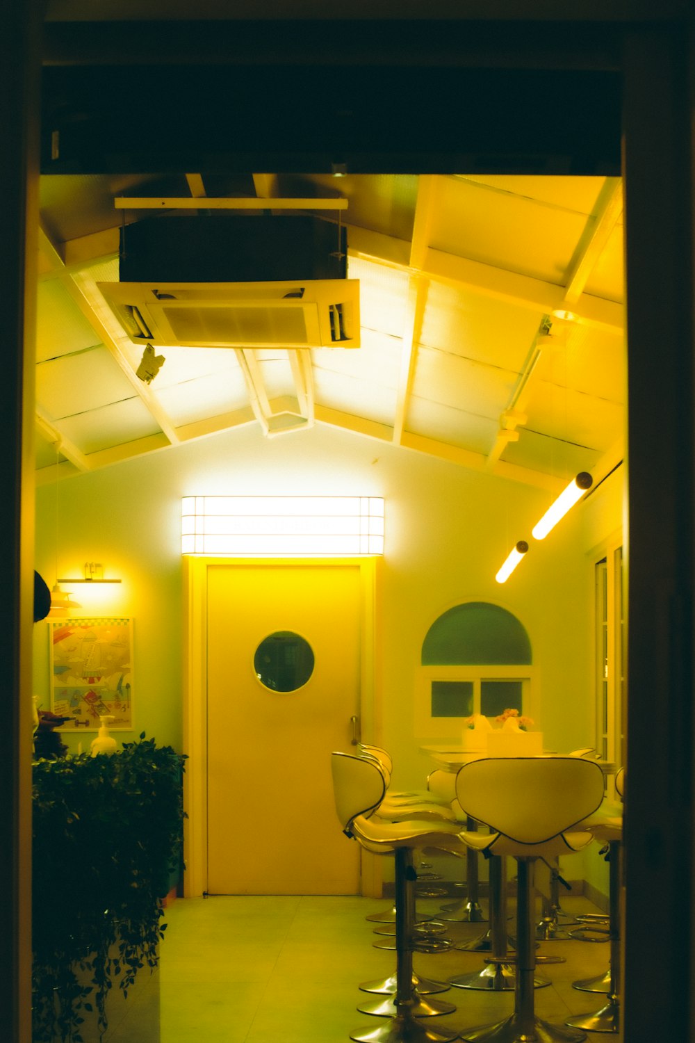 a yellow room with three chairs and a television