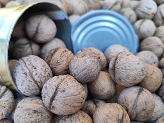 Raw walnuts spilling from an elegant linen sack onto a clean white surface with gentle shadows