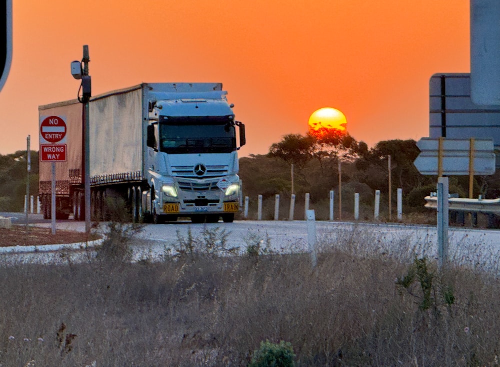 a semi truck driving down a rural road