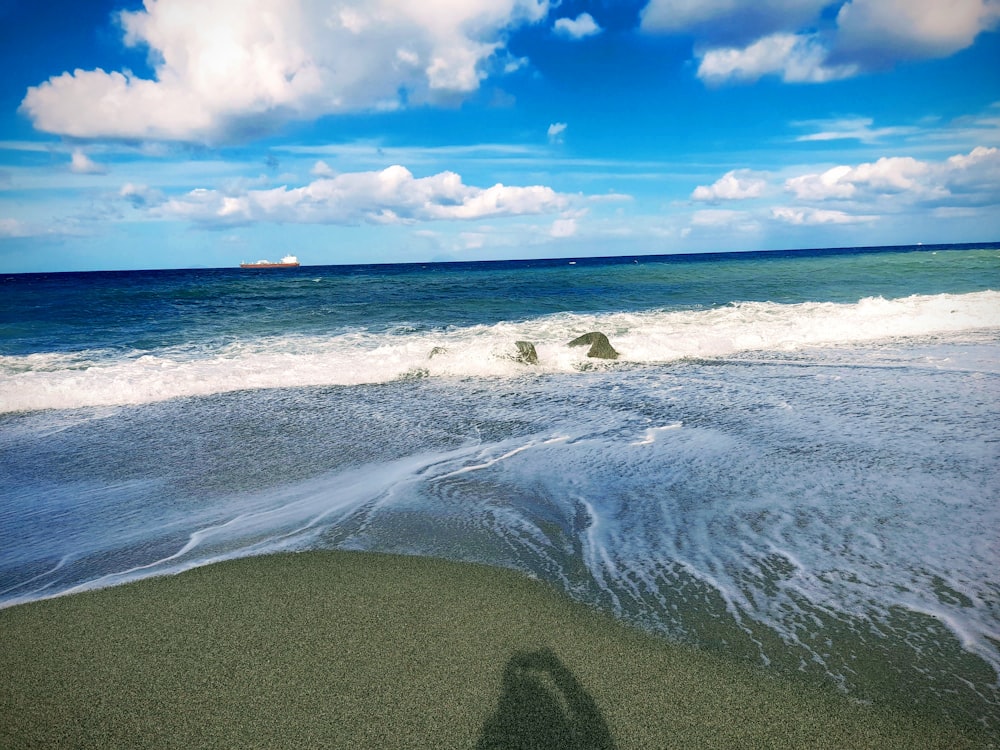 a shadow of a person standing in the surf