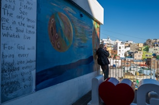 Close-up of a reporter interviewing a community member in front of a colorful mural.