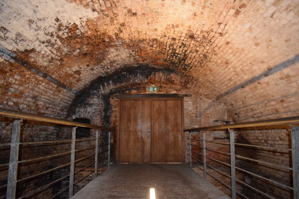 a tunnel with a wooden door and metal railings