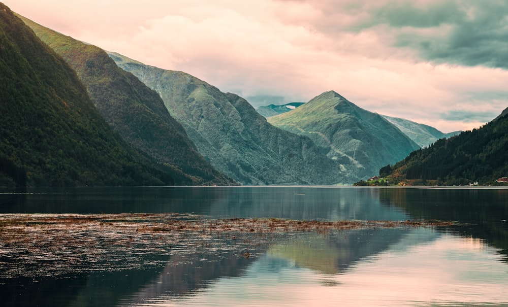 a body of water surrounded by mountains under a cloudy sky