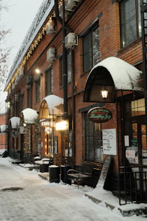 A cozy snow-covered main street in Brinkerton, Michigan, glowing warmly under soft evening lights.