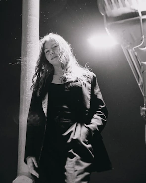 Monochrome image capturing a candid moment of a street musician playing under a lamppost.