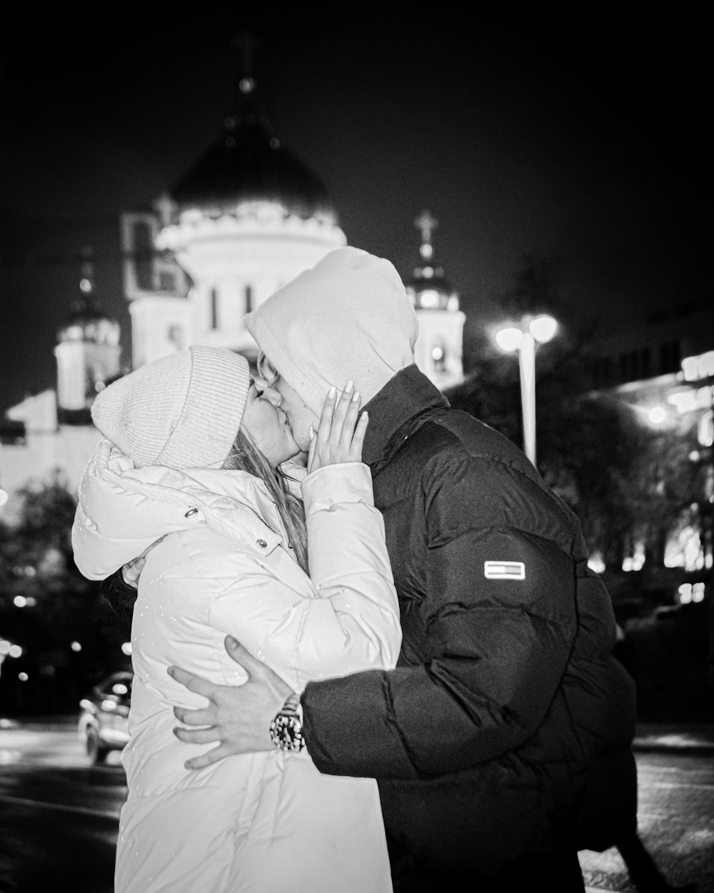a man and woman kissing in front of a building