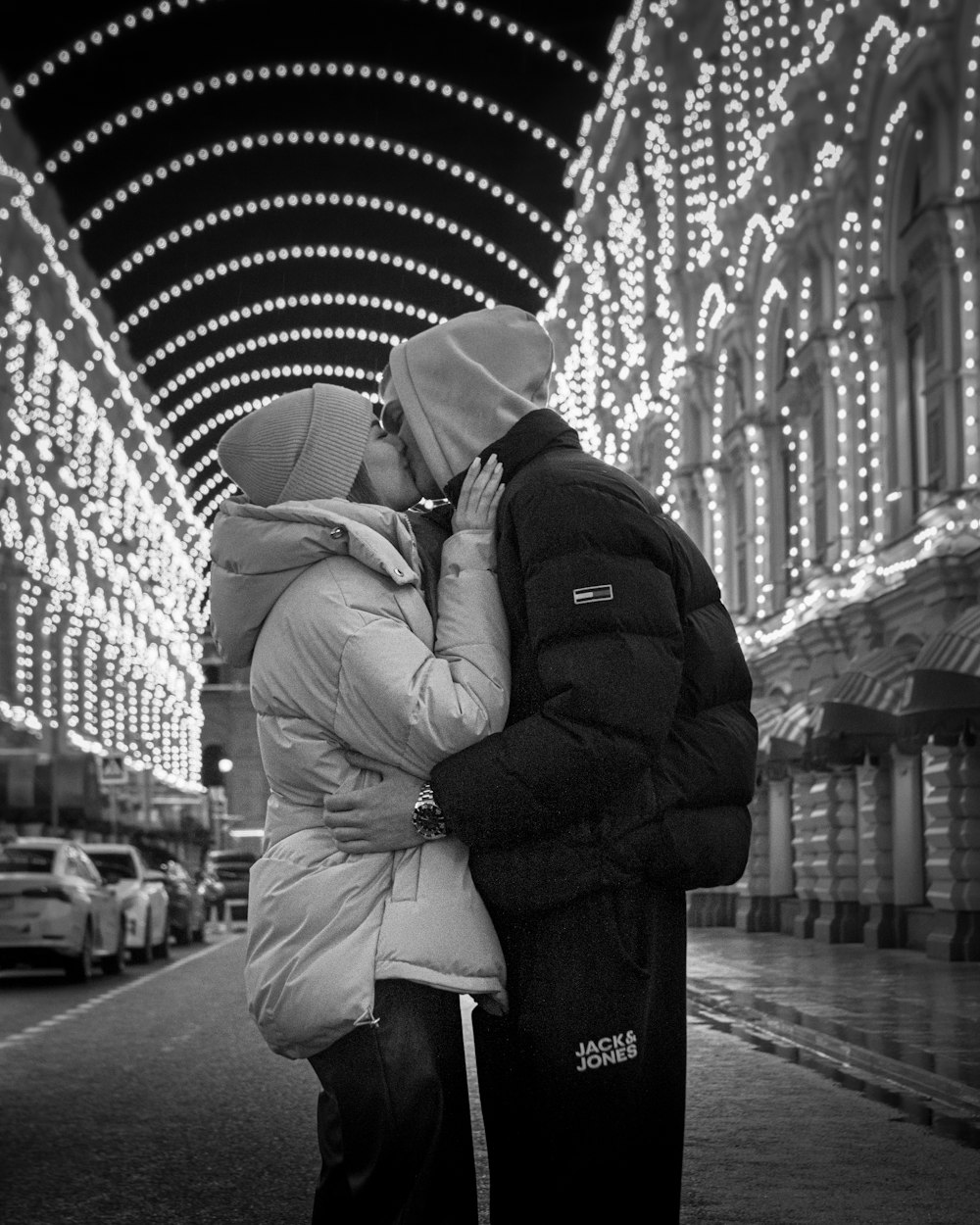 a man and woman kissing in front of christmas lights