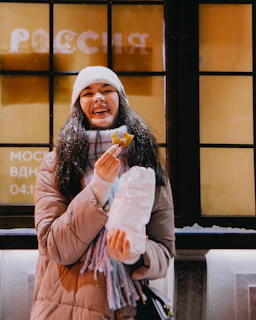 Smiling customer holding a Crustella pastry box outside a cozy kitchen window.