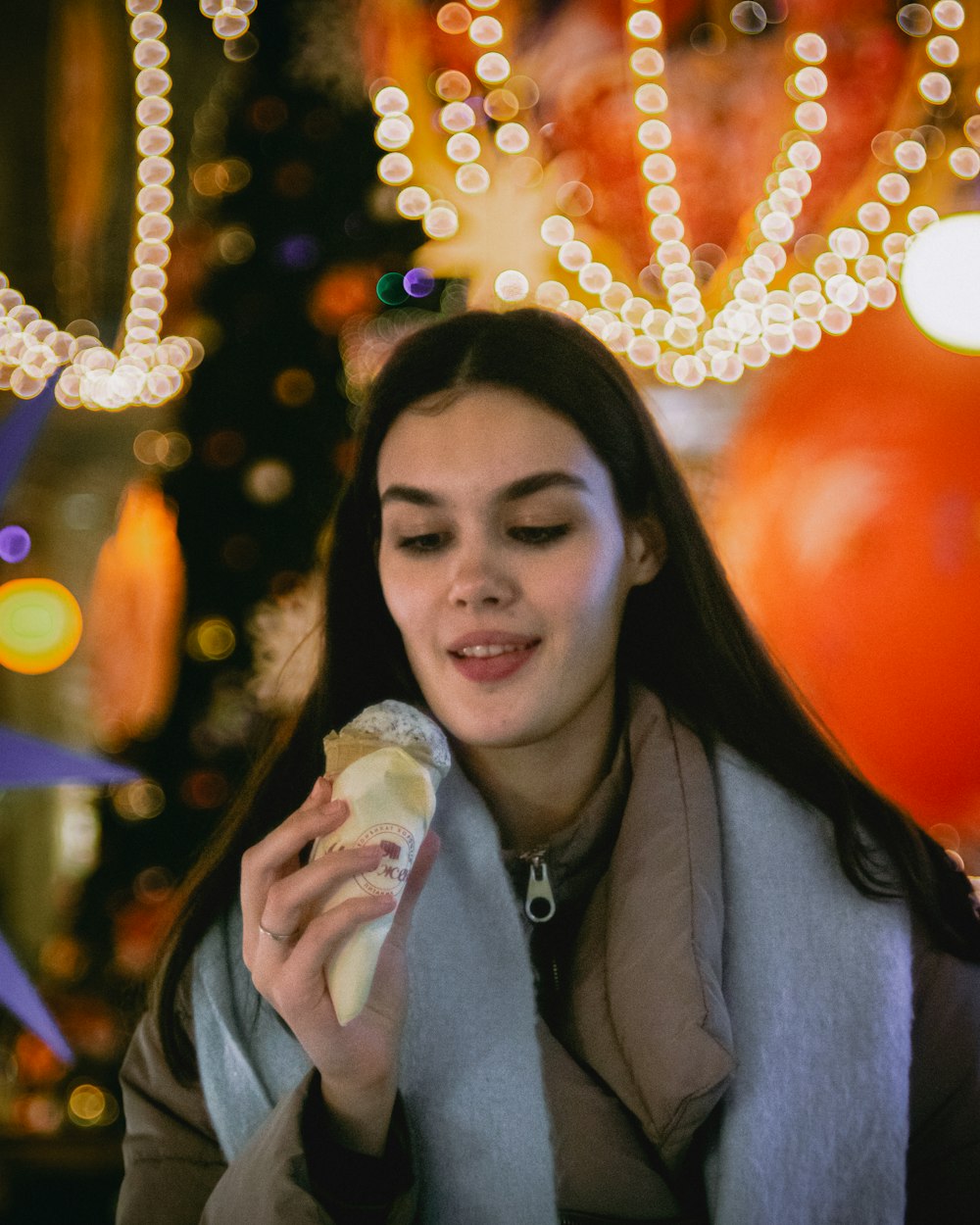 a woman eating a hot dog in front of a christmas tree