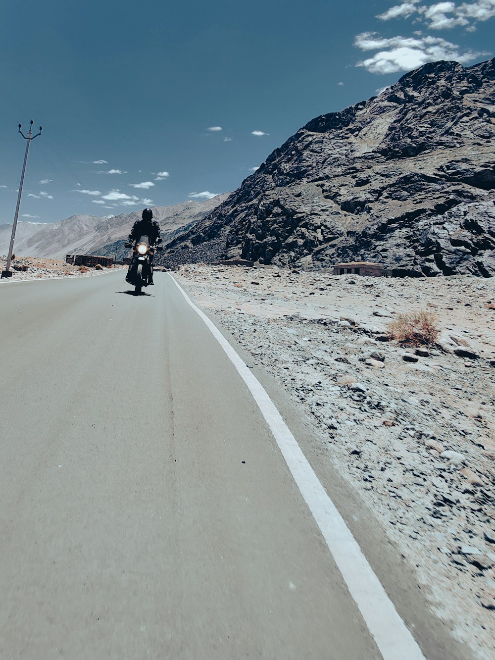 a man riding a motorcycle down a desert road