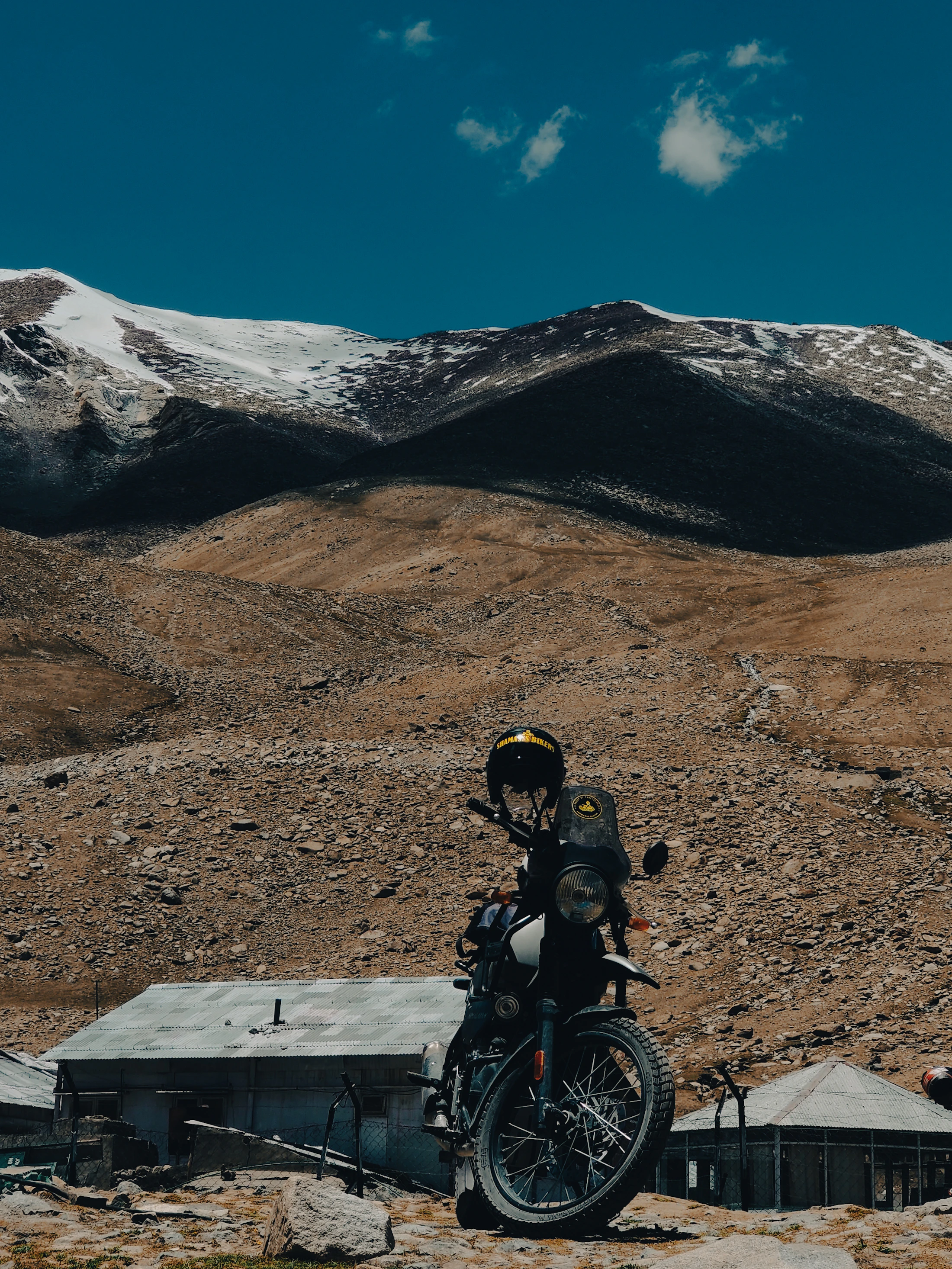 A motorcycle parked beside a roadside shelter on a high Himalayan pass