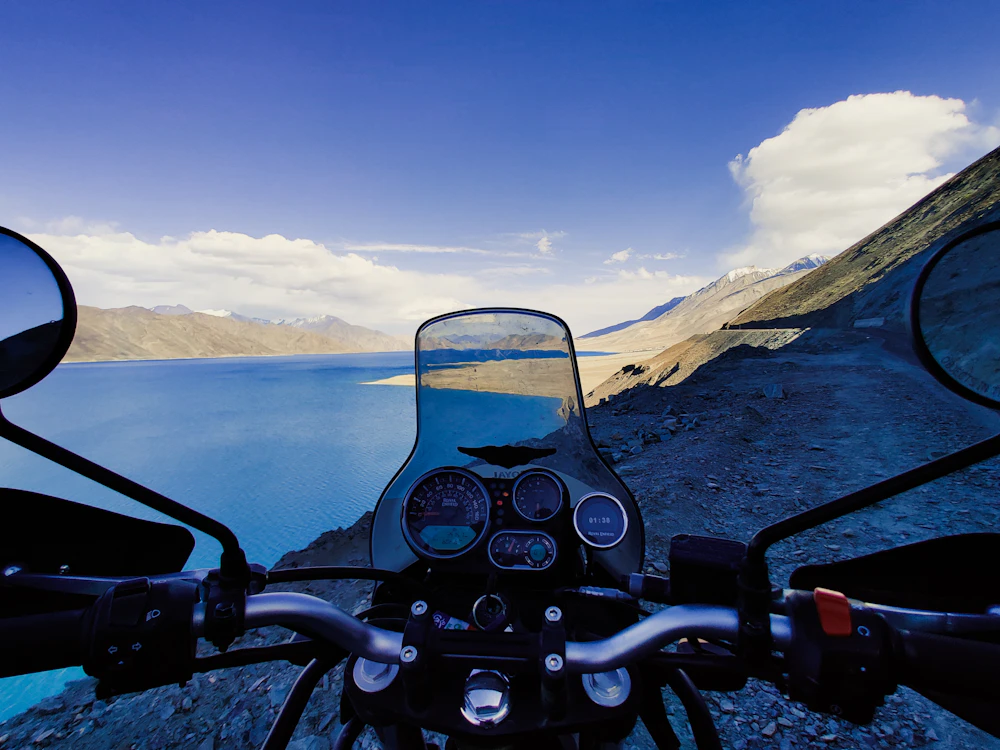 View of a Himalayan lake and mountains from the seat of a motorcycle in Nepal
