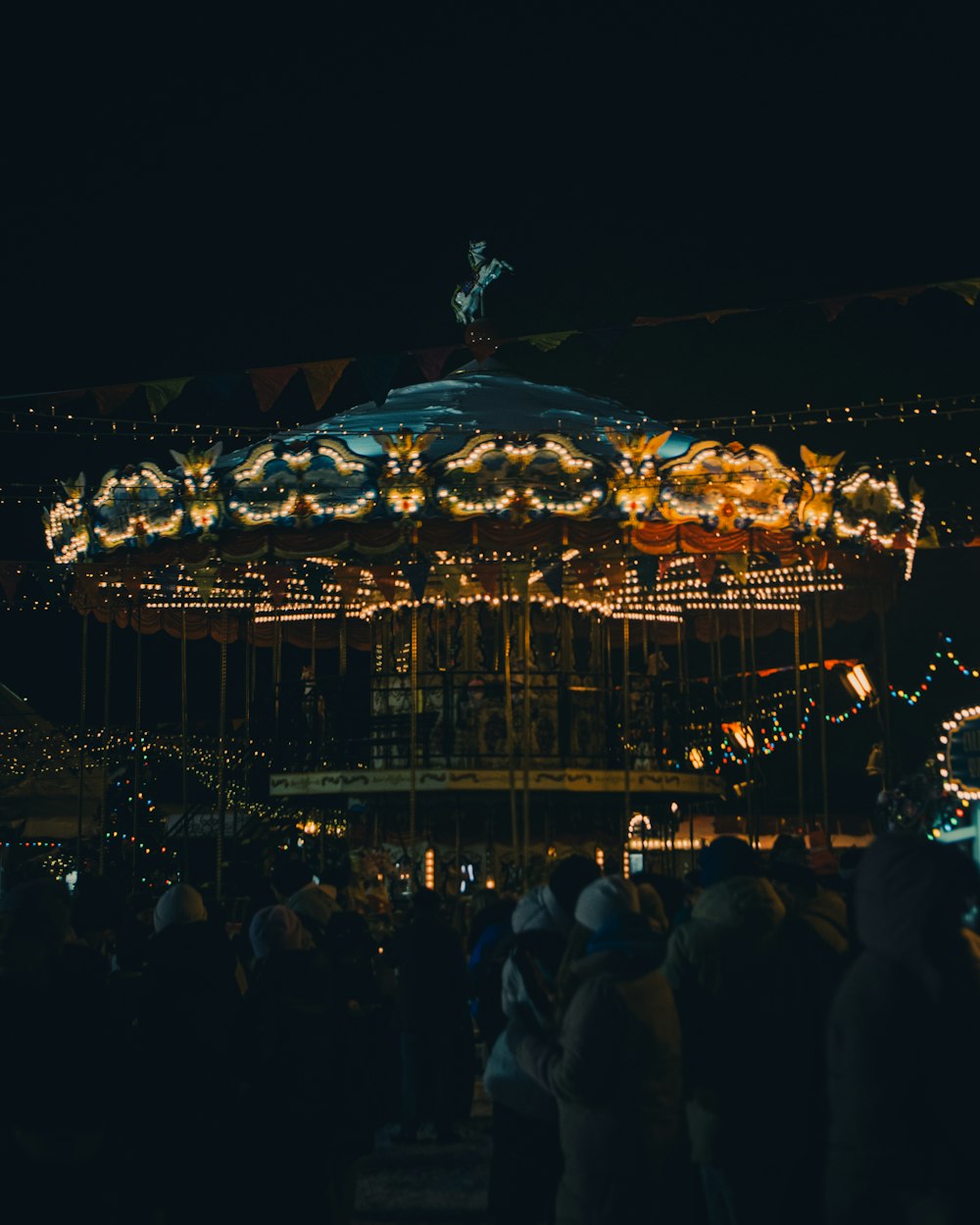 a crowd of people standing around a merry go round