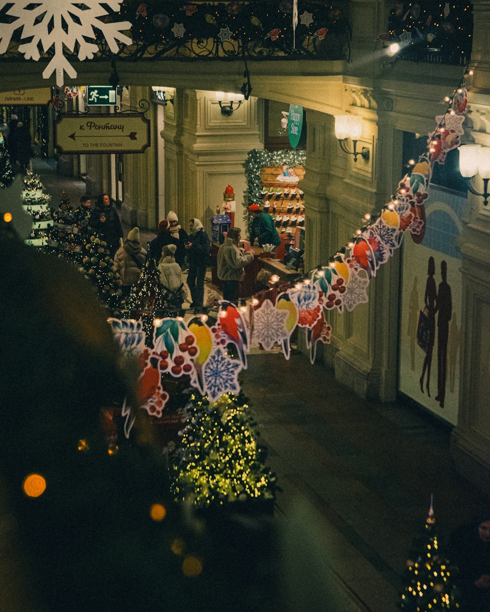a group of people walking down a street next to christmas decorations