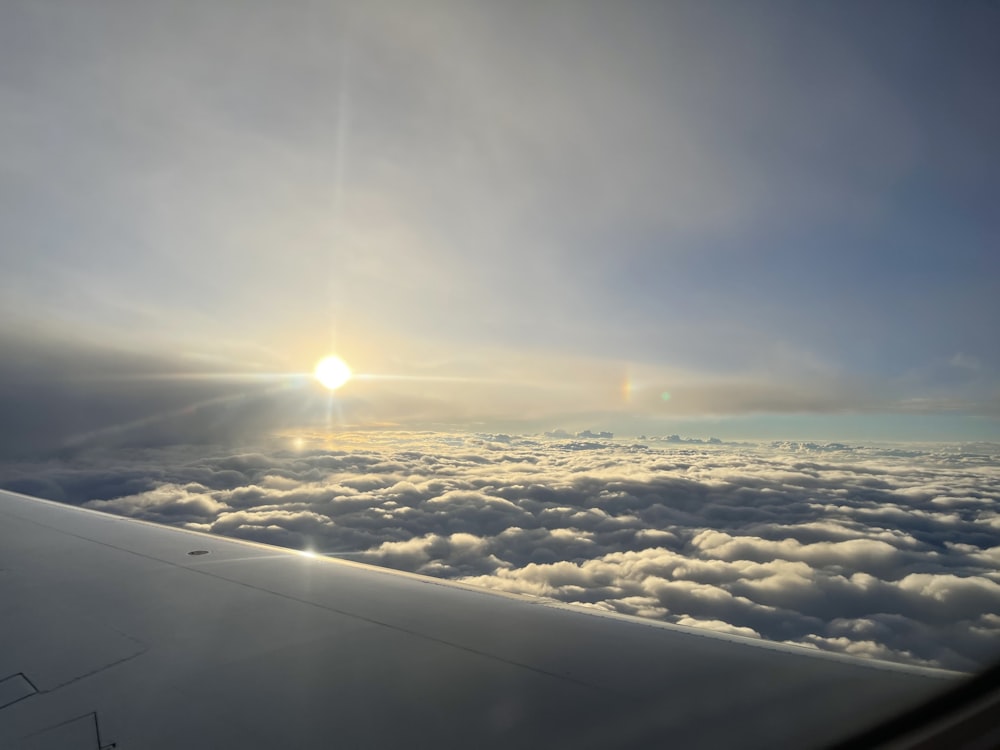 the sun is shining over the clouds from an airplane window