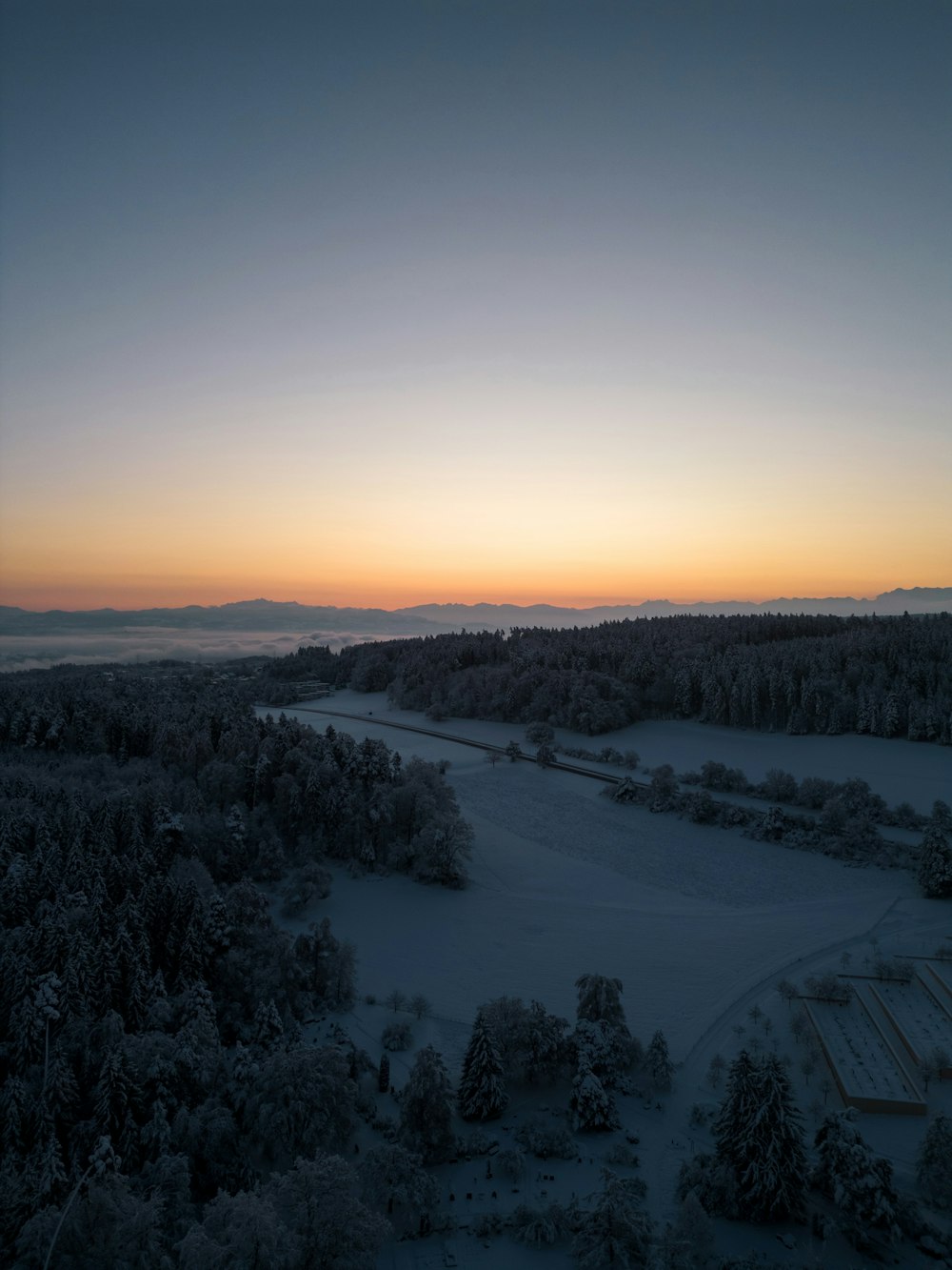 the sun is setting over a snowy landscape