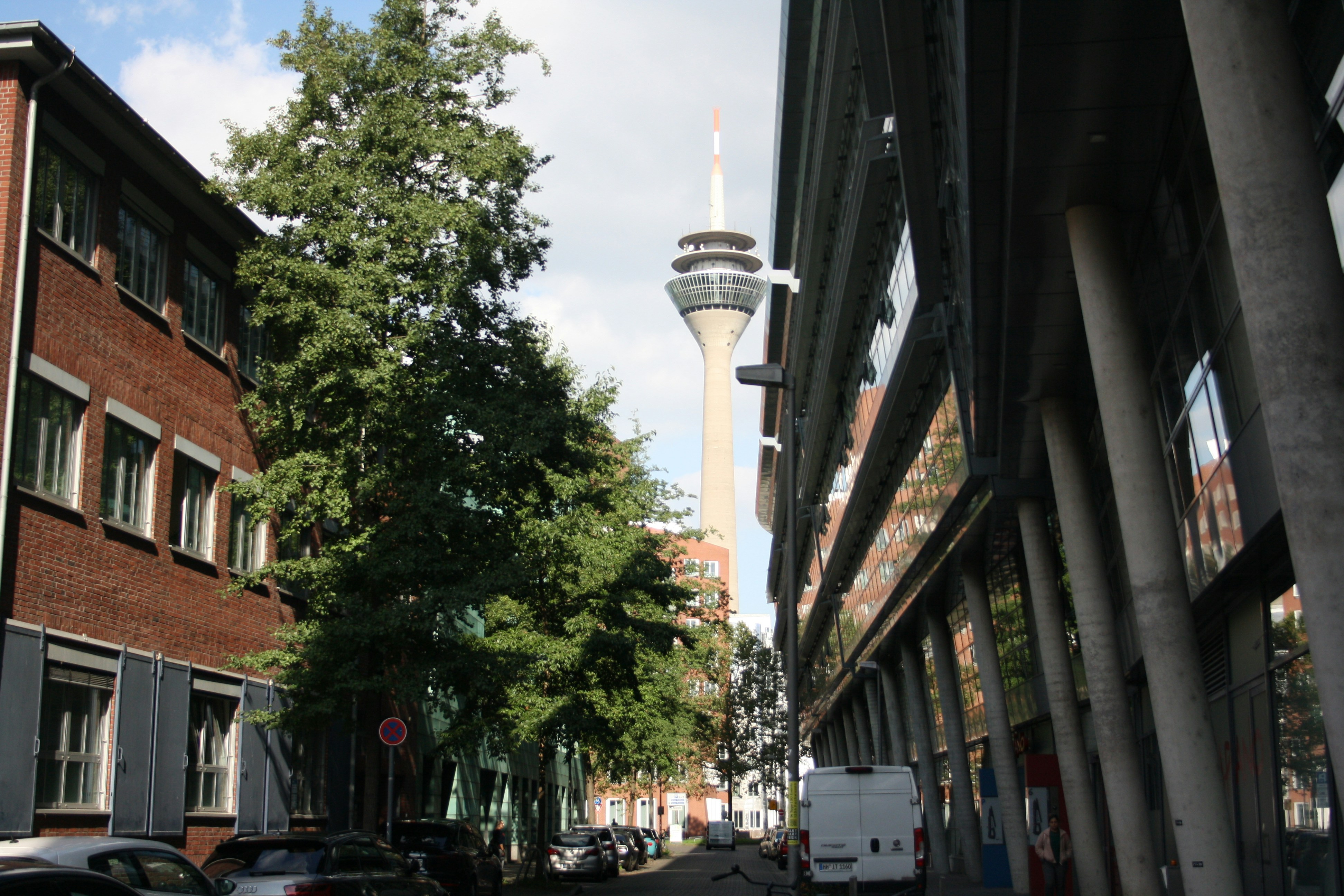 a street with cars parked on both sides and a tall tower in the background